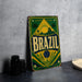 A vintage-style metal sign with the word "BRAZIL" prominently displayed, featuring a tropical landscape with palm trees and a sun.