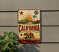 A vintage-style sign with the word "CALIFORNIA" prominently displayed, featuring a sun, palm trees, and a bear.