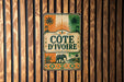 a vintage-style sign with a tropical theme, hanging on a wooden wall.