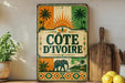a vintage-style sign with a tropical theme, including palm trees and a sun, mounted on a wall next to a wooden cutting board and some potted plants.