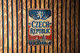 A vintage-style metal sign with the text "Czech Republic" displayed prominently, featuring a lion and a castle-like structure.
