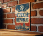 A vintage-style metal sign with the text "Czech Republic" displayed prominently, mounted on a brick wall.