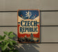 A vintage-style sign for the Czech Republic, featuring a lion and a castle, is displayed on a wall.