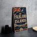 A vintage-style metal sign with the text "Falkland Islands" and a Union Jack flag, along with a seagull and other nautical elements, is displayed on a gray countertop.