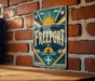 A vintage metal sign with the word "FREEPORT" displayed prominently, featuring a sun and palm tree design, is mounted on a brick wall.