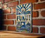a vintage-style metal sign with a blue and white color scheme, mounted on a brick wall.