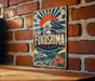 A vintage metal sign with a mountain and sun design, mounted on a brick wall.