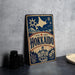 A vintage-style metal sign with the name "Hokkaido" prominently displayed, featuring a star and snowflake design, along with a small illustration of a building and a cow.