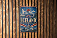 A vintage-style sign with the word "ICELAND" prominently displayed, featuring a mountain landscape and a sunburst design.