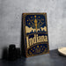 A vintage-style metal sign with the word "Indiana" prominently displayed, featuring a city skyline and a torch-like symbol.