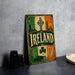 A vintage-style metal sign with the word "IRELAND" prominently displayed, featuring various Irish symbols and landmarks such as a castle, a harp, and a shamrock.