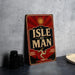 A vintage-style sign with the text "ISLE OF MAN" is displayed on a table, accompanied by a stack of black camera lenses and a white dish.