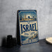 A vintage-style metal sign with the word "ISRAEL" prominently displayed, featuring an illustration of a cityscape and a sunburst design.