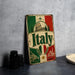 A vintage-style metal sign with the word "Italy" prominently displayed, featuring a combination of green, red, and white colors, along with images of landmarks and architecture.