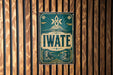 A vintage-style sign with the word "IWATE" prominently displayed, mounted on a wooden wall.