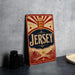 A vintage Jersey beer sign is displayed on a table, featuring a red and gold design with a crown and sun motif.