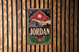 A vintage-style metal sign with the word "JORDAN" prominently displayed, featuring a stylized illustration of a city skyline and a star.