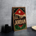 A vintage-style metal sign with the word "JORDAN" prominently displayed, featuring a silhouette of a building and mountains in the background.