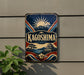 A vintage-style sign for "Kagoshima" is displayed on a wall, featuring a sun, mountain, and traditional Japanese architecture.