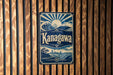 A sign for Kanagawa, featuring a sun and wave design, is displayed on a wooden wall.