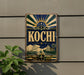 A vintage-style sign with the word "Kochi" prominently displayed, featuring a sunburst design and various nautical elements.
