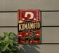 A vintage-style sign for Kumamoto, featuring a red background with a white circle and a temple-like structure, along with Japanese text and imagery.
