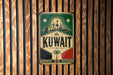 A vintage-style sign with the word "KUWAIT" prominently displayed, featuring a city skyline and a palm tree.