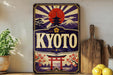 A vintage-style sign for "KYOTO" featuring a sun and pagoda design, surrounded by Japanese-inspired elements such as cherry blossoms and a temple.