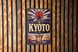 A vintage-style sign for "KYOTO" is displayed on a wooden wall, featuring a red sun and a temple-like structure.