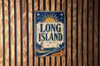 A vintage metal sign with the text "LONG ISLAND" and a lighthouse illustration is displayed on a wooden wall.