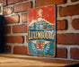 A vintage metal sign with the word "LUXEMBOURG" prominently displayed, featuring a castle and a lion, mounted on a brick wall.
