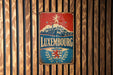 A vintage metal sign with the text "LUXEMBOURG" and a graphic of a castle, placed on a wooden wall.