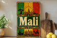 a vintage-style metal sign with the word "Mali" prominently displayed, surrounded by various cultural elements such as a sun, buildings, and a camel.