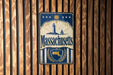 A vintage metal sign with the text "Massachusetts" and a lighthouse illustration is displayed on a wooden wall.