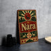 A vintage-style metal sign with the name "Nara" displayed prominently, featuring a deer and other decorative elements.