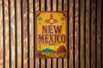A vintage metal sign with the text "NEW MEXICO" is displayed on a wooden wall.