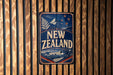 A vintage-style sign that reads "NEW ZEALAND" is displayed on a wooden wall.