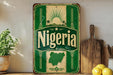 a vintage-style sign with the word "Nigeria" prominently displayed, along with a map of Nigeria. The sign is placed on a shelf next to a wooden cutting board and a potted plant.