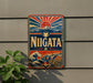 A vintage-style sign with the word "NIGATA" prominently displayed, featuring a sun and mountain landscape design.