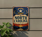 A vintage-style metal sign with the text "NORTH CAROLINA" displayed prominently, mounted on a wall.