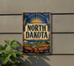 A vintage metal sign with the text "NORTH DAKOTA" and a sun-like design, mounted on a wall.