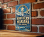 A vintage-style metal sign with the text "NORTHERN MARIANA ISLANDS" is displayed on a brick wall.