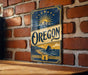 A vintage-style metal sign with the word "OREGON" prominently displayed, featuring a mountain landscape and sunburst design.