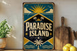 A vintage-style sign for "Paradise Island" is displayed on a shelf, accompanied by a potted plant, a wooden cutting board, and some lemons.