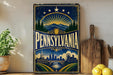 A vintage-style sign for Pennsylvania featuring a sunburst design, mountains, and a city skyline.