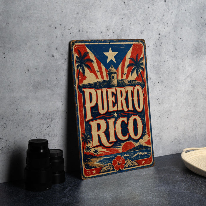A vintage-style metal sign with the text "PUERTO RICO" prominently displayed, featuring a red, white, and blue color scheme with a star and palm trees. The sign is placed on a gray surface, with a stack of black camera lenses and a white dish visible in the background.