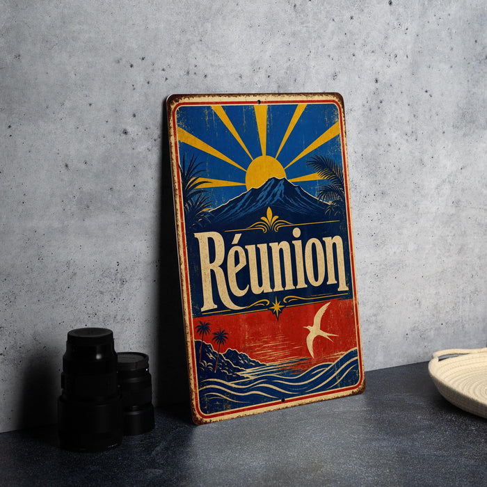 A vintage metal sign with a colorful design, featuring a sun, palm trees, mountains, and the word "Reunion" prominently displayed.