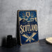 A vintage-style metal sign with the word "SCOTLAND" prominently displayed, featuring a shield, a lion, and a castle in the background.
