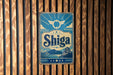 A vintage-style sign with the word "Shiga" prominently displayed, featuring a castle and mountains in the background.