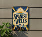 a sign for "Spanish Wells" hanging on a wall.